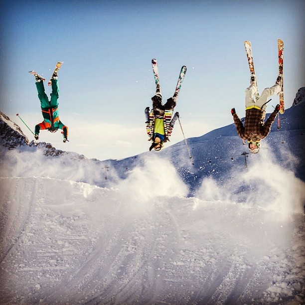 three skiers doing tricks