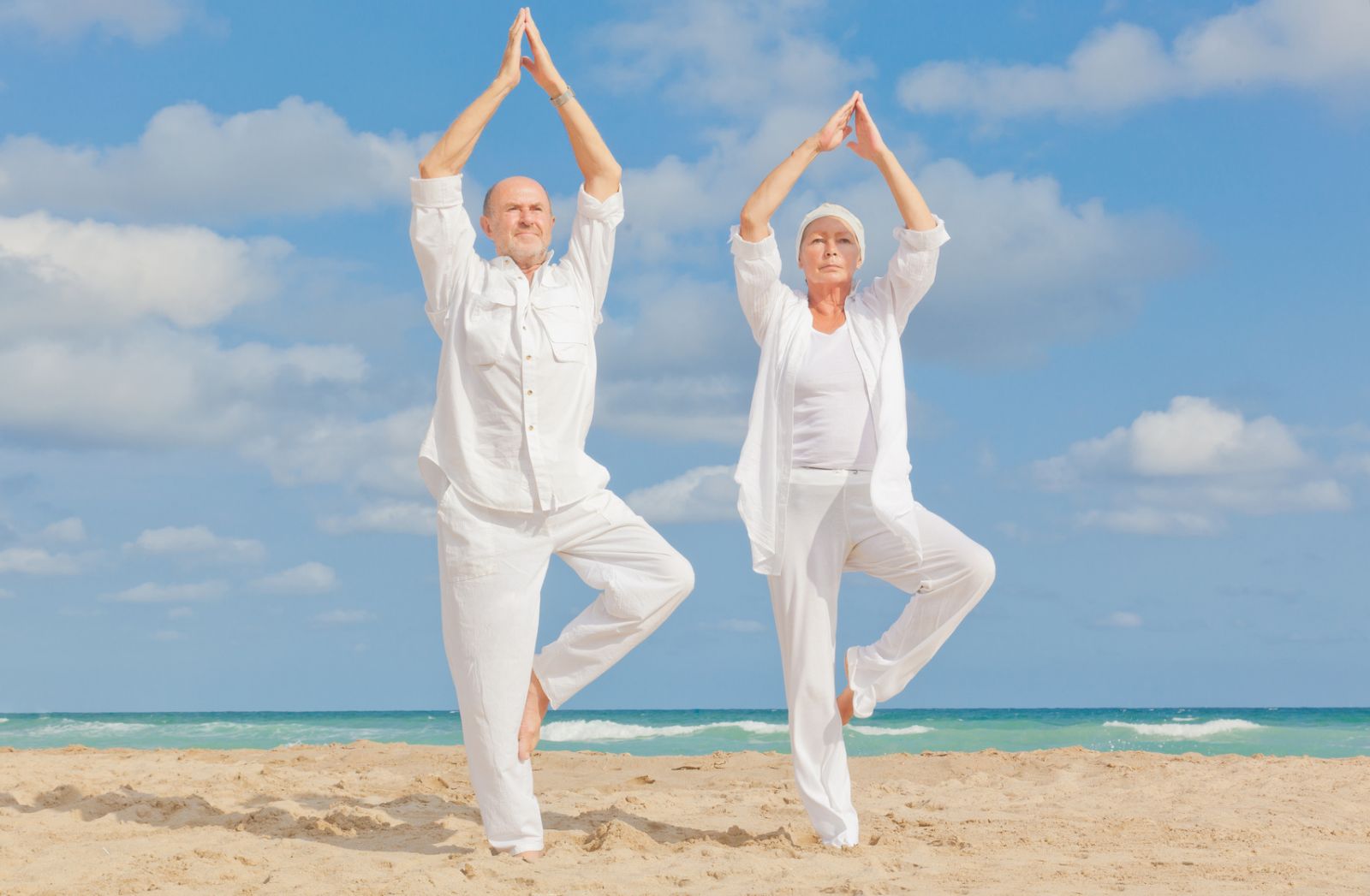 an old couple doing yoga on the beach