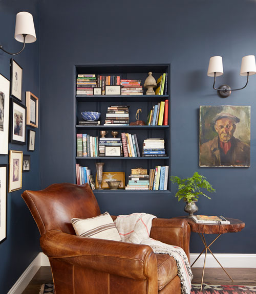 cozy reading chair country style reading nook on blue wall brown sofa wooden table portrait pictures on the wall