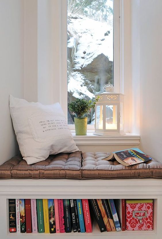 cozy reading nook with small windows and snoy view books under sofia