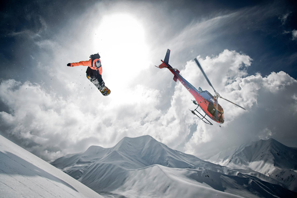 Snowboarder-jumping-with-helicopter-on-background-ski-movie-ski-resorts-holidays