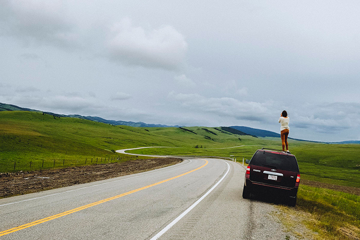 Woman on car taking pictures from Cowboy Trail Road trip in Canada 