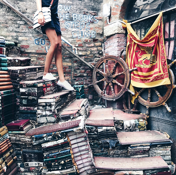 Girl stepping down into Libreria Acqua Alta Bookstore