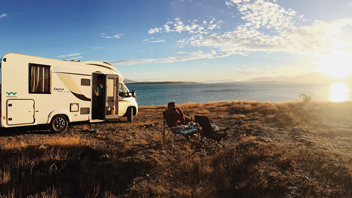 Man with camper on road trip having a break at sunset 