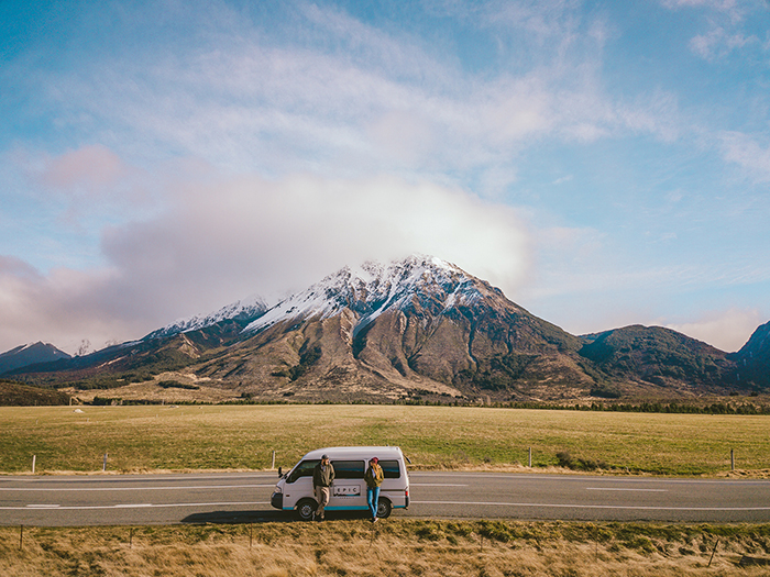 Couple with small bus having a break on south island road trip