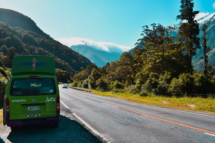 Green small bus travelling on South Island road trip