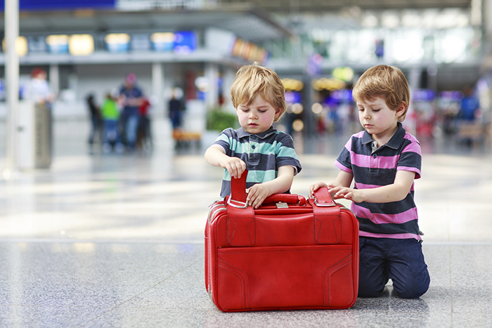 Two kids with red luggage on the airport