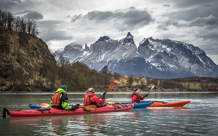 People kayaking in Torres del Paine National Park with mountains as a background