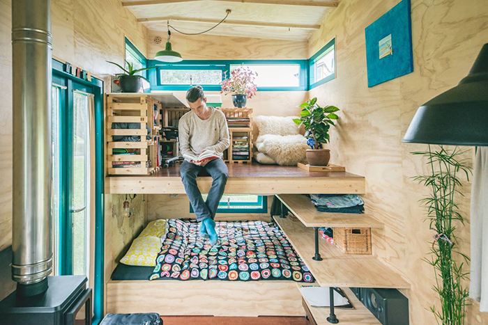 Man hanging from second floor in tiny wooden house