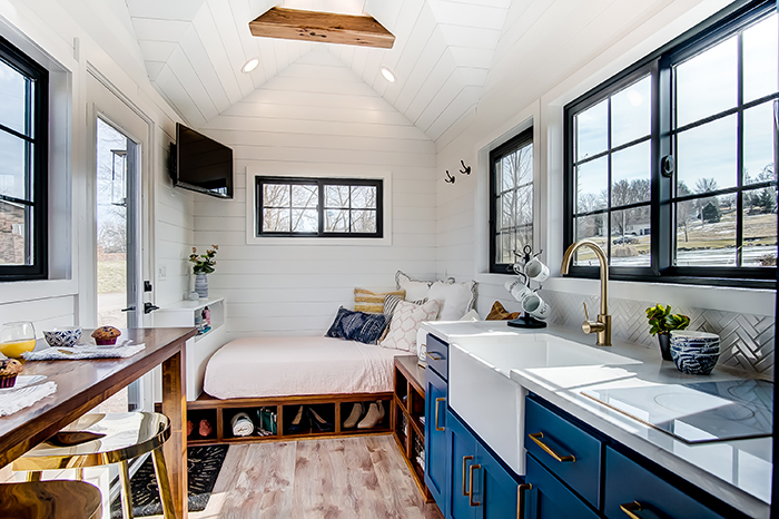 One floor tiny house with blue kitchen and wooden table