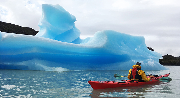 Man kayaking near iceberg in Torres del Paine National Park, Chile