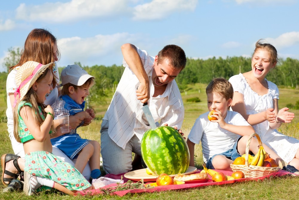 Family on a picnic and the father cutting a big watermelon