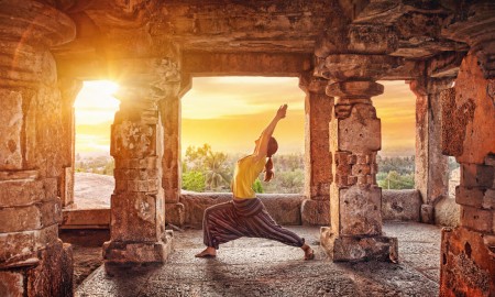 Woman doing yoga on a sunset among ancient ruins in India