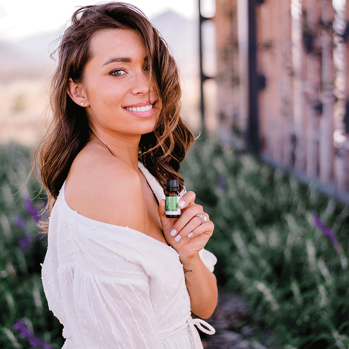 Girl with small essential oil in her hand smiling outside