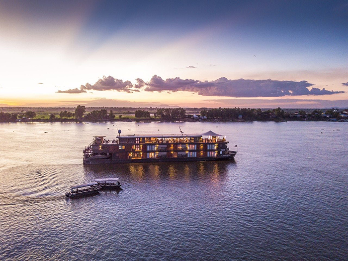 Floating hotel in Vietnam on a sunset and two small guest boats next to it