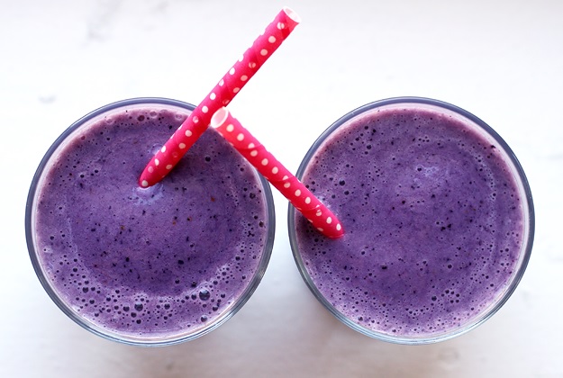 Two glasses full of smoothies with two straws
