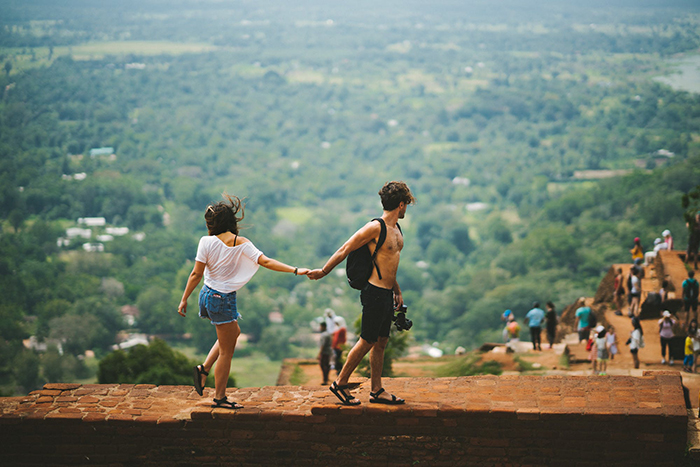 Couple holding hands and walking on a wall while looking at the good nature in front