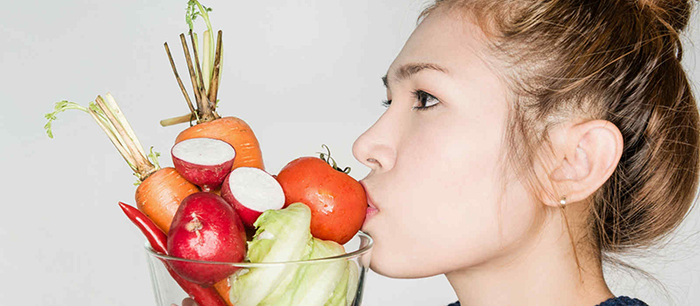 Woman holding a glass basket filled with vegetables