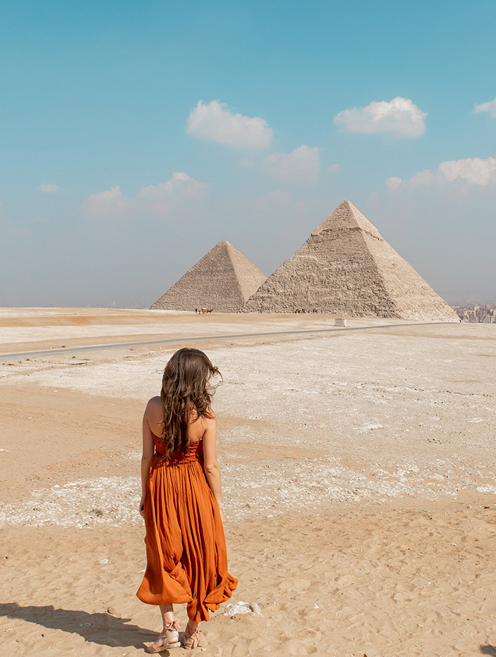 Woman in a dress turned with the back looking at the pyramids