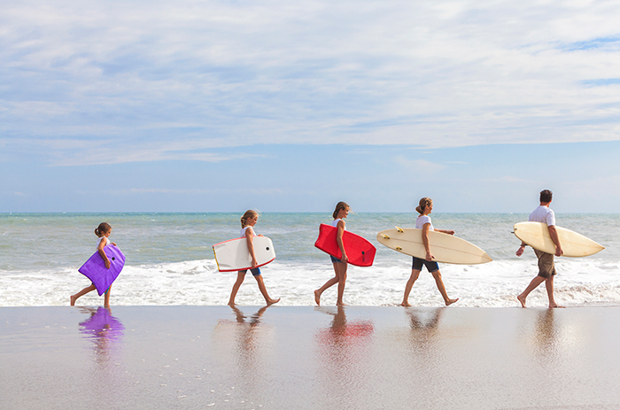 Family surfers walking on a beach in Portugal while holding their surfboards