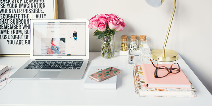 Beautiful flowers on a work desk put next to the laptop and surrounded with cute notebooks 