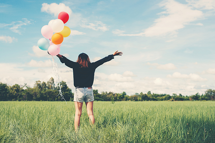 Woman with balloons in a meadow