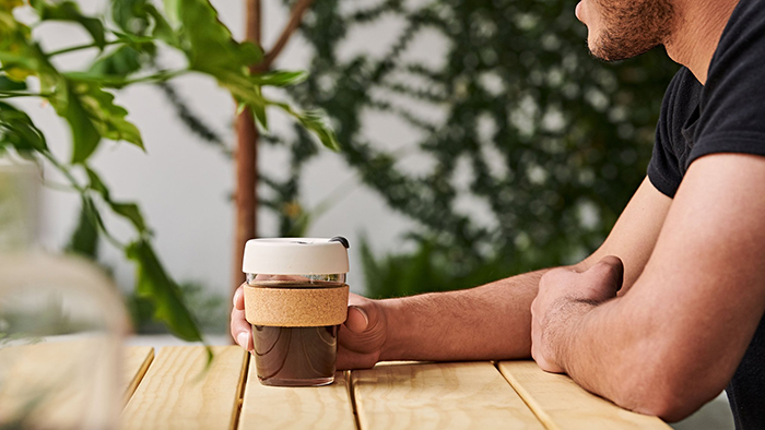 Man sitting and drinking coffee from reusable cup