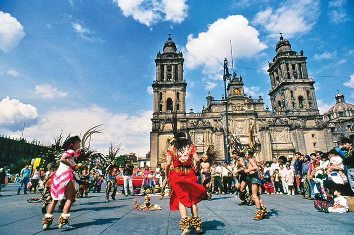 People in traditional clothes dancing in front of a cathedral in Mexico