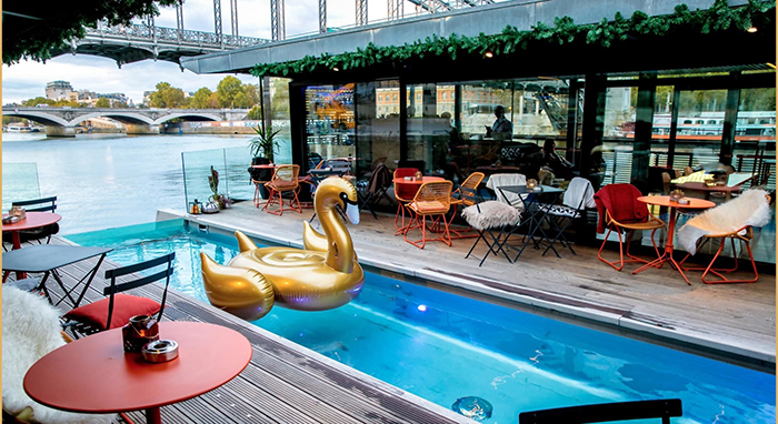 Bar in a floating hotel in France with a small pool inside and a swan toy in it