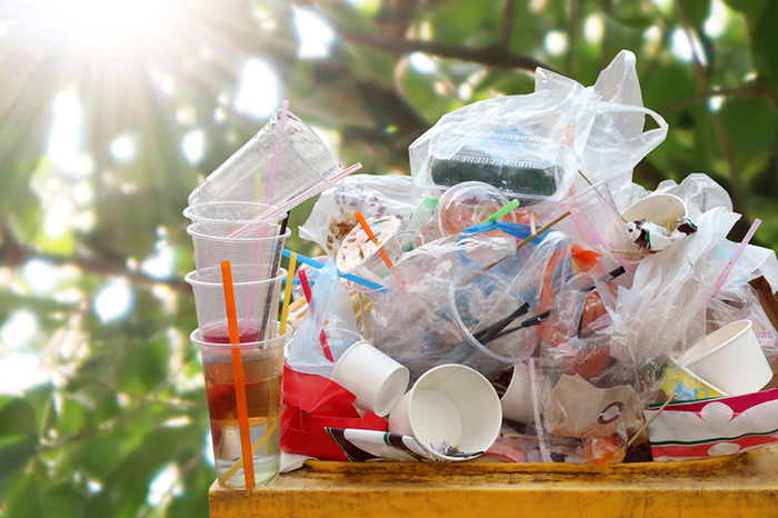 Plastic cups and drinking straws in a trash bin