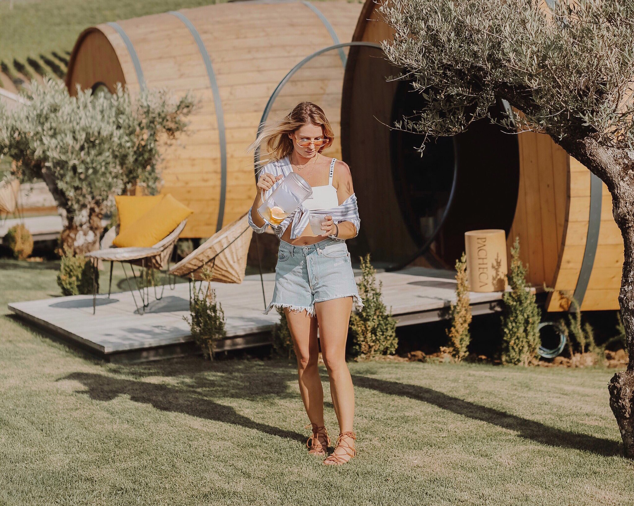 Woman standing outside of a wine barrel room while sipping fruit water in her glass