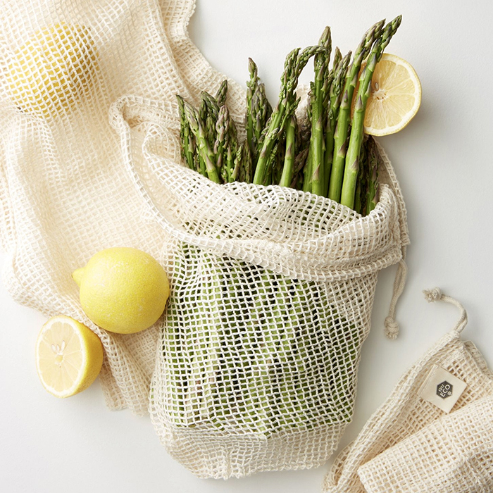 Reusable grocery bag filled with asparagus and lemon