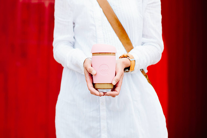 Woman in a dress holding a reusable coffee mug