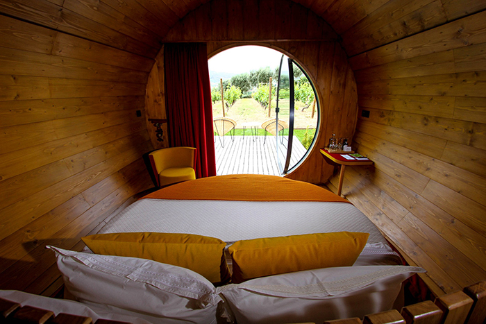 Bed, small table and chair inside of the wine barrel room