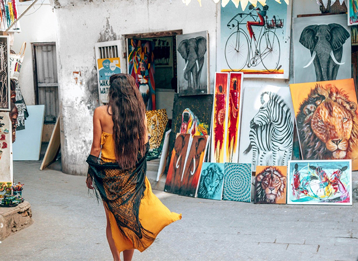 Woman wandering around Stone Town and an art house next to her