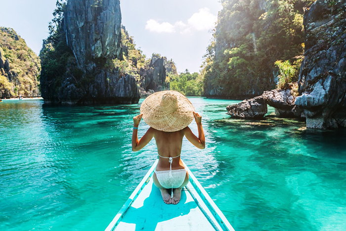 Woman on a small boat around the clean waters and rocks in The Philippines