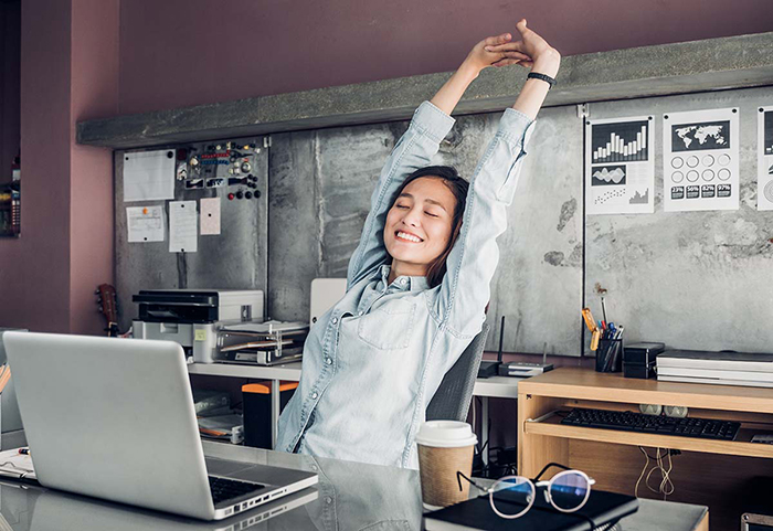 Woman stretching at her work place with closed eyes