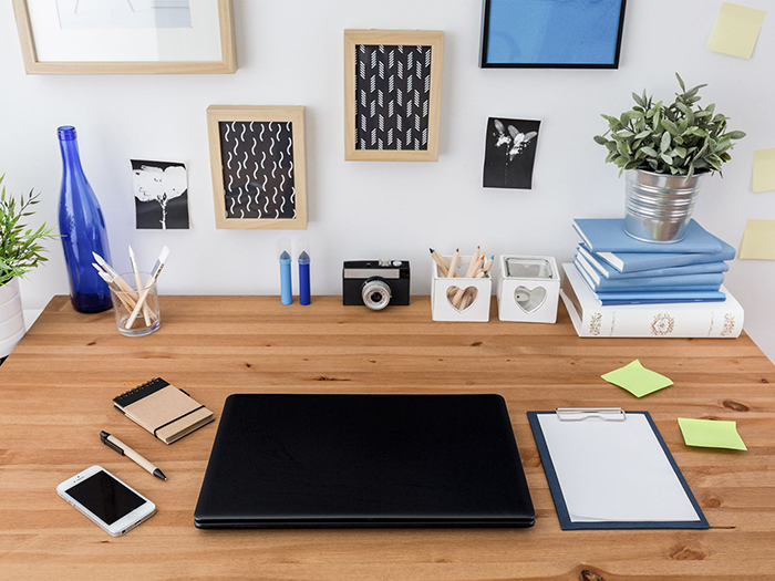 Work desk nicely organized with picture frames, notebooks and flowers