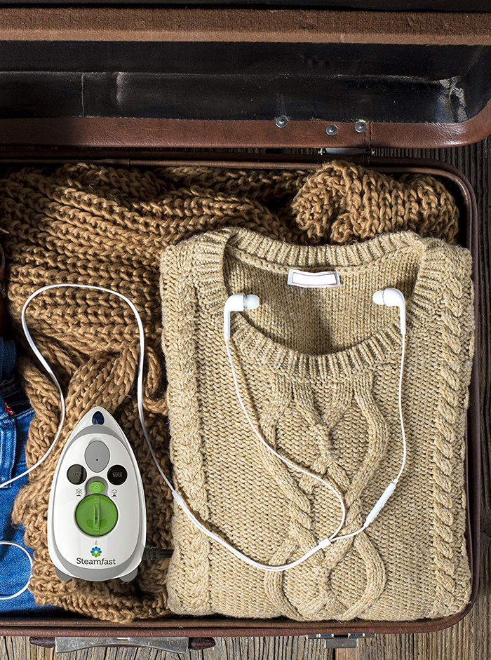 Luggage with mini iron travel steam, brown sweater and headphones