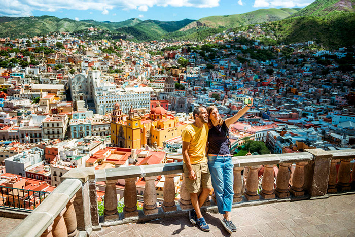 Couple taking a picture on a balcony with Cabo San Lucas behind