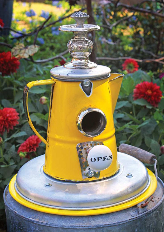 Bird house in a big old kettle with nice flowers in the background