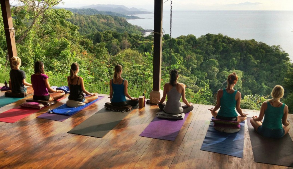 Women doing yoga in a resort with a forest and sea view