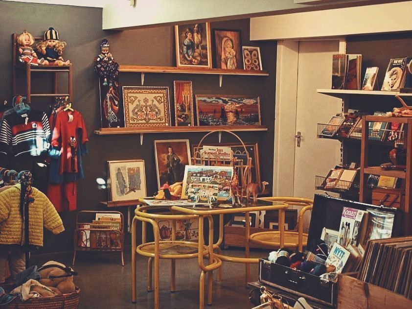 Second-hand shop full of vintage pictures, books, kids' clothes and a table in the middle