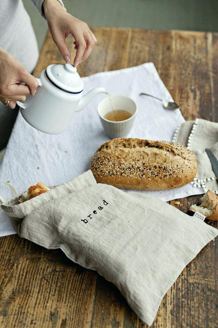 Linen bread bag on a table and a woman sipping tea