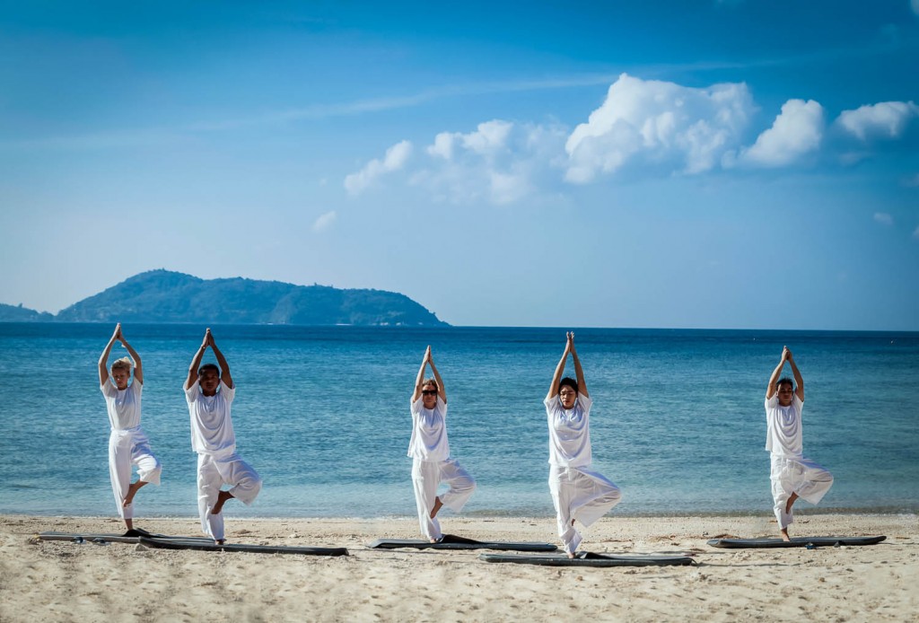 People practicing yoga on open air with an ocean view