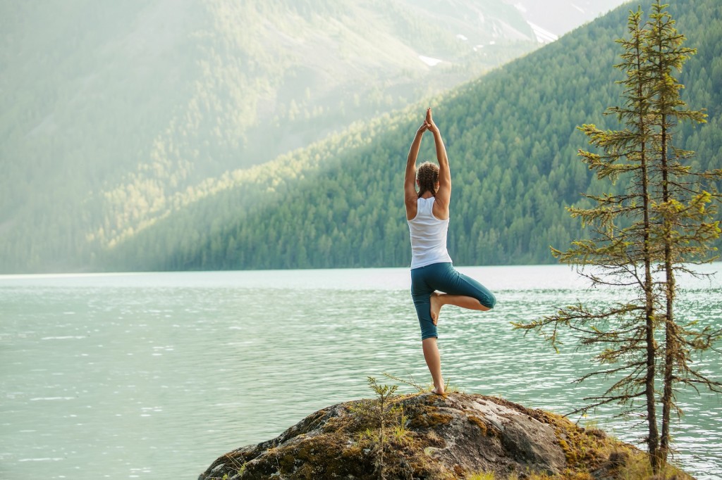 Girl practicing yoga by the sea surrounded with calm nature