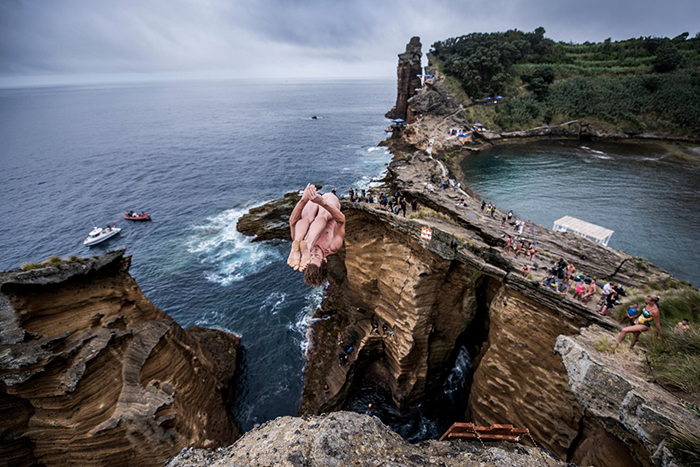 Man jumping into the waters surrounded with rocks