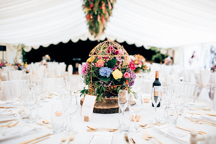 Different kind of flowers on the wedding table accompanied with a bottle of wine and glasses