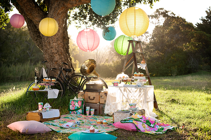 Retro picnic blanket with cushions around it, nice table, bikes and tree decor