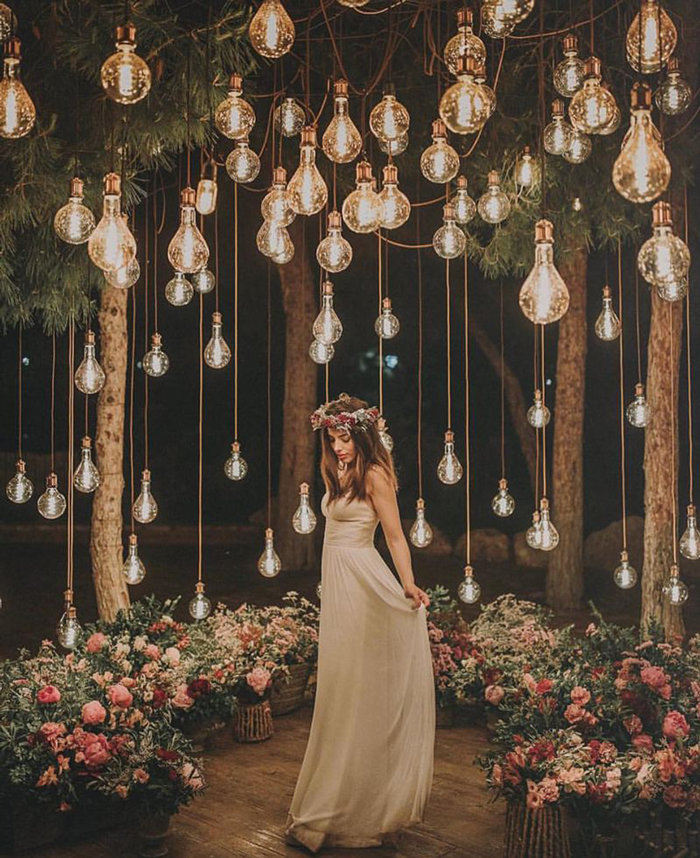 Bride standing surrounded by flowers and cozy lights